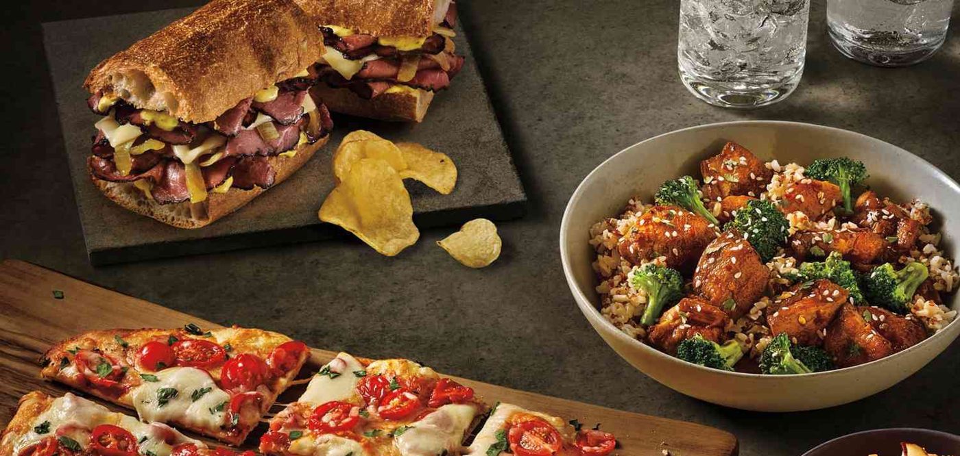 Flatbread pizza with cherry tomatoes and mozzarella, a grilled sandwich and a hot bowl